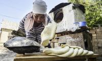 Kyrgyzstan. In the village of Bagysh, some 500 km from Bishkek. Eliza Kokozova (Kyrgyz family) - at home, cooking, bakes bread.  © FAO/Vyacheslav Oseledko